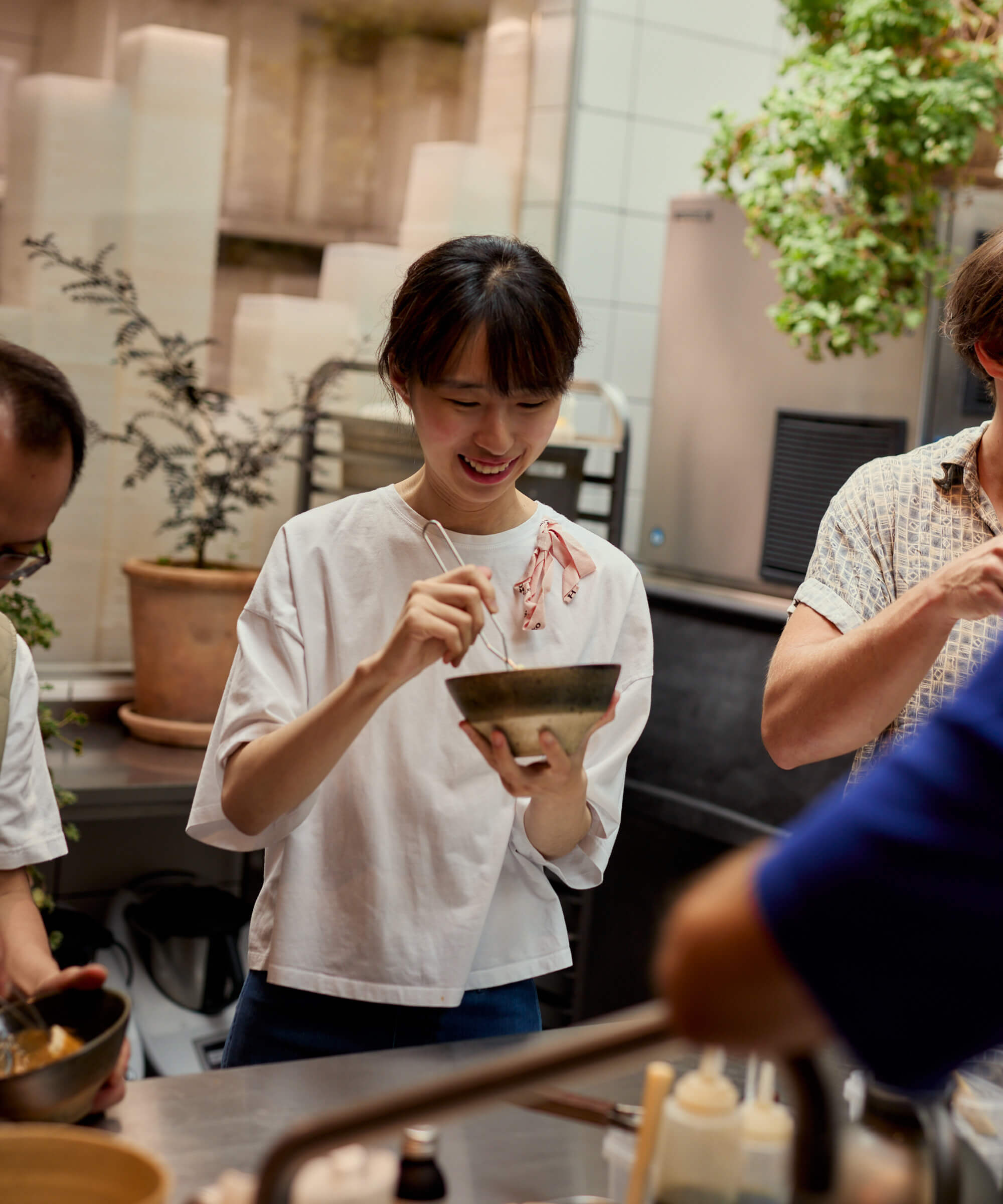 People in a kitchen setting with one person holding a bowl and smiling.